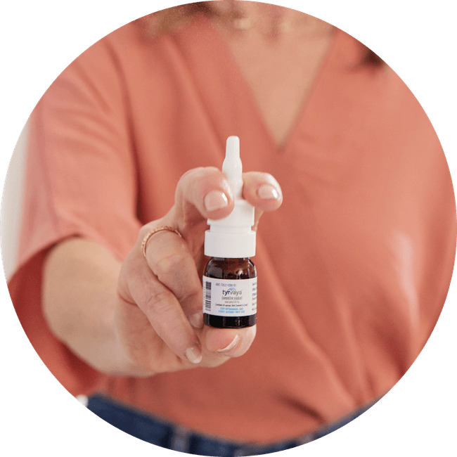 Image of person holding a 4.2 mL bottle of Tyrvaya® (varenicline solution) nasal spray